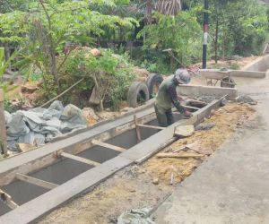 Anggota Satgas TMMD 115 Plester Parit jalan yg telah dibuat